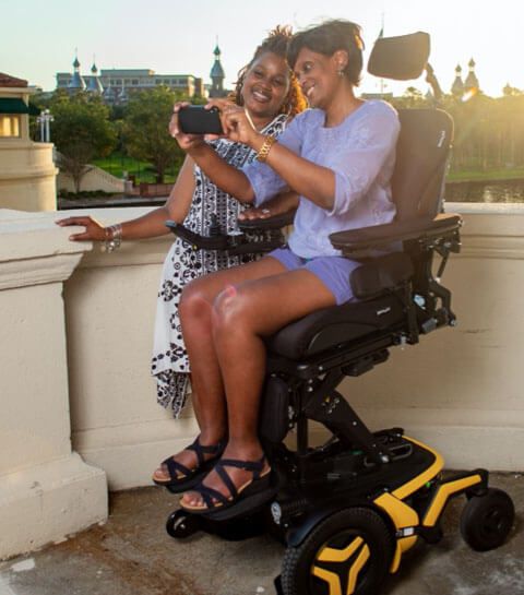 Person på ett hjälpfordon från Permobil med en stående person bredvid