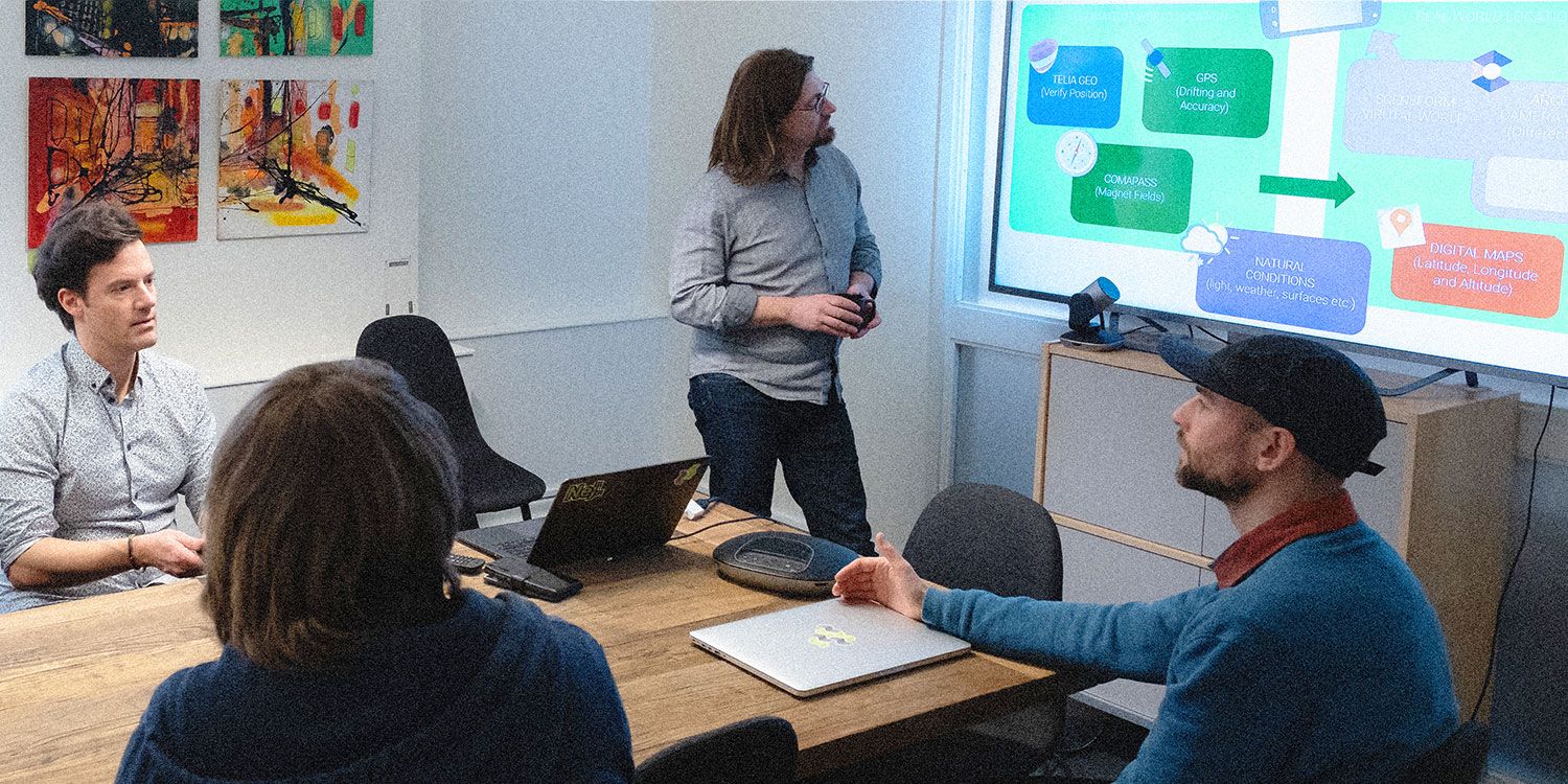 Medarbetare på Devize vid mötesbord och en presentation på en stor bildskärm