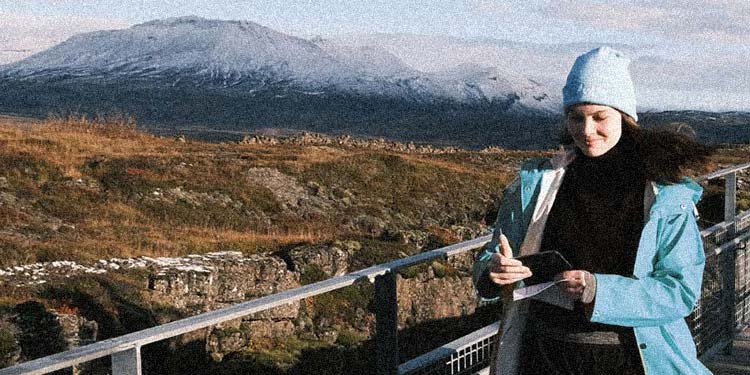 Medarbetare på Devize promenerar med en mobiltelefon, med en karg slätt och snöklädda berg i bakgrunden